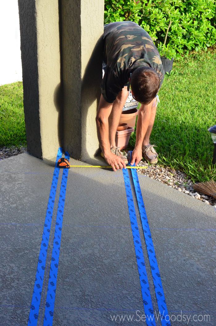 Man taping out and measuring tape on a patio floor.
