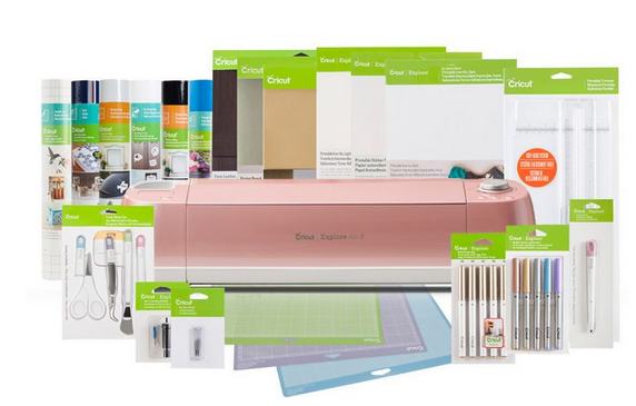 Pink Cricut Explore Air 2 with mats, pens, and other materials.