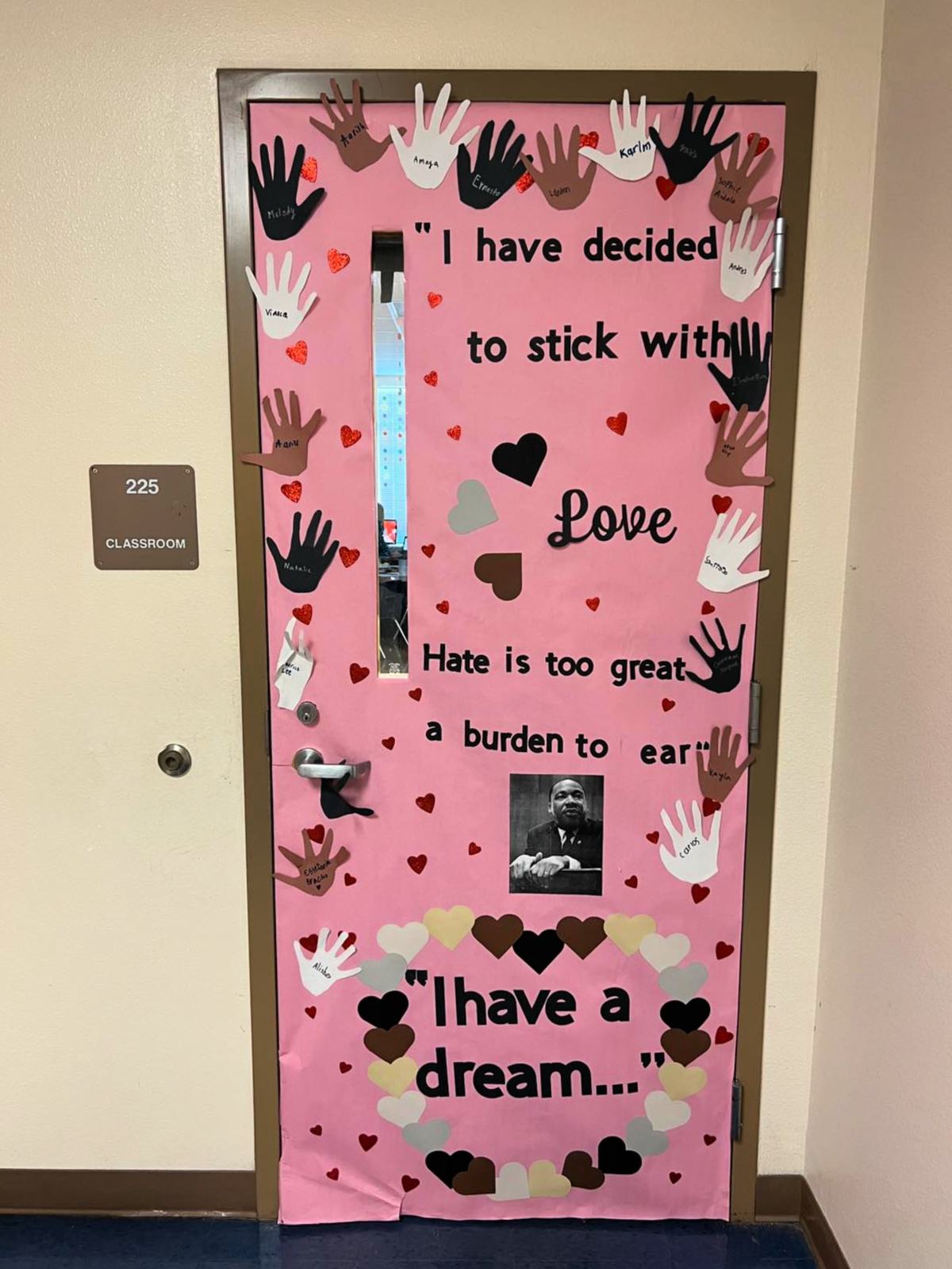 Pink door with hands cut out and names of kids on the door with a photo of MLK and "I have a dream" quote on door.