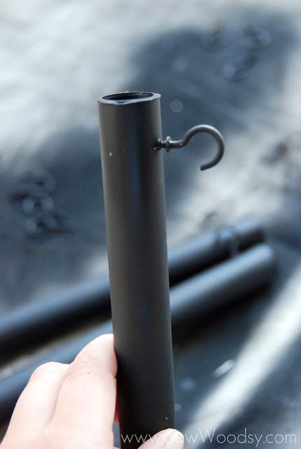 Black pole with a black hook being held by a hand.