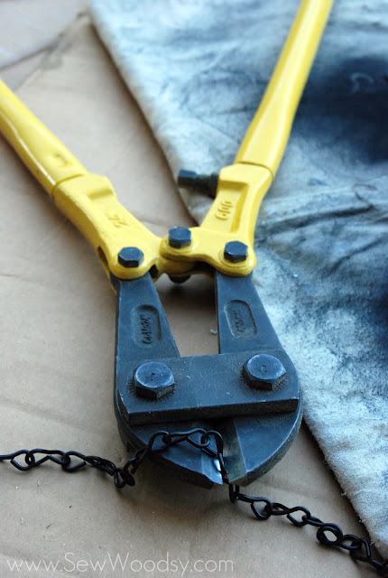 Bolt cutters with a black chain in the clamp.