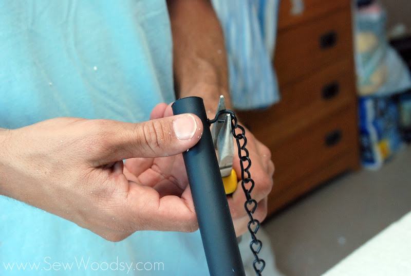 Man holding a black PVC pipe with pliers closing the hook.