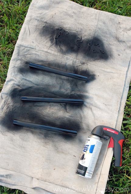 Drop cloth on grass with three pvc pipes and hooks sprayed black.