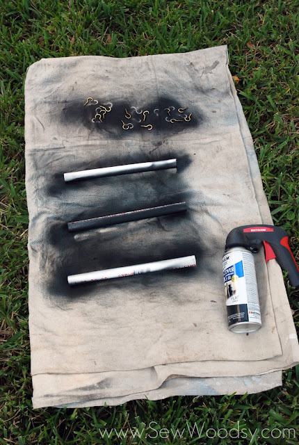 Drop cloth with three pieces of PVC and hooks with spray paint next to it.