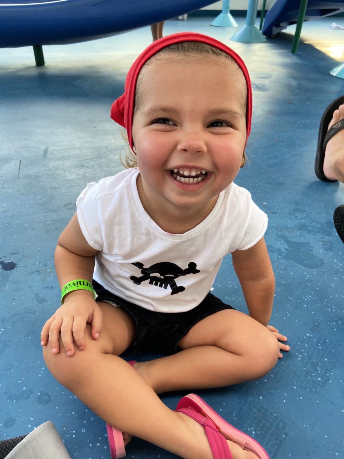 Toddler dressed in a pirate outfit sitting on a blue and white speckled floor.