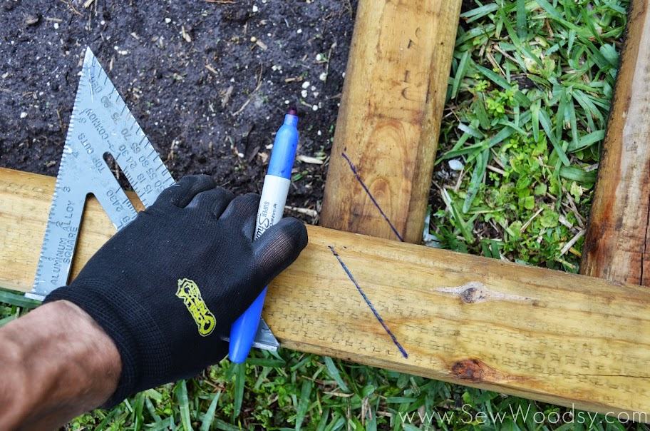 Hand in black glove holding a blue sharpie, marking lines to cut.