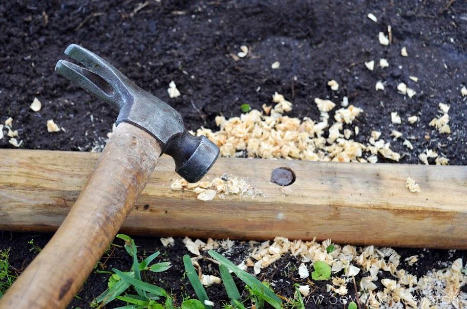 Hammer hammering rebar in a wood post on the ground.