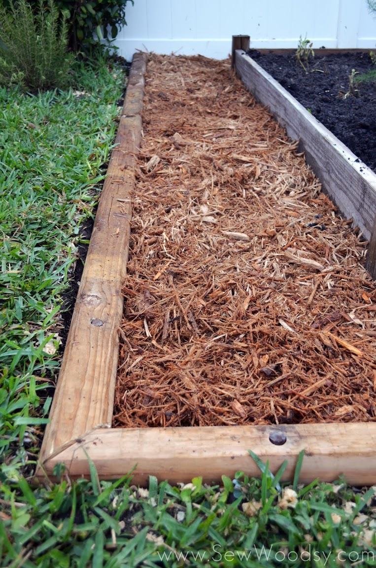 green grass with wood timber edge and mulch with raised garden bed.