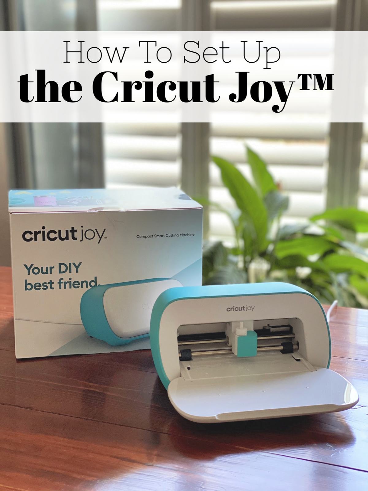 Cricut Joy resting on a wood table with Cricut Joy box behind it.