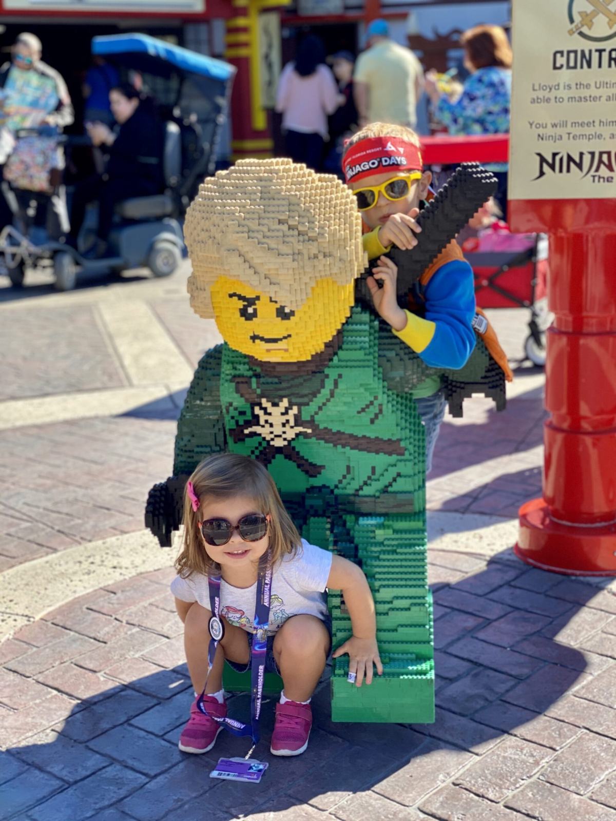 Little girl sitting on Ninjago life size brick figure.