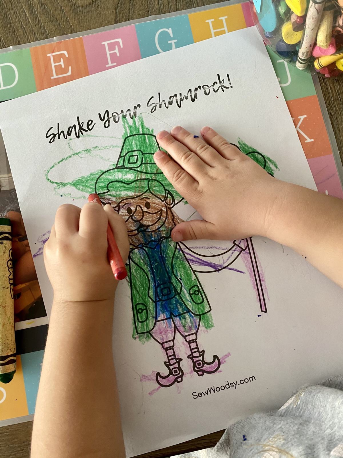 Child's hand colring a st. patrick's day coloring sheet.