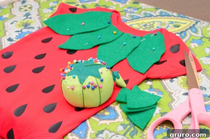 Arranging green felt leaves on the onesie's neckline