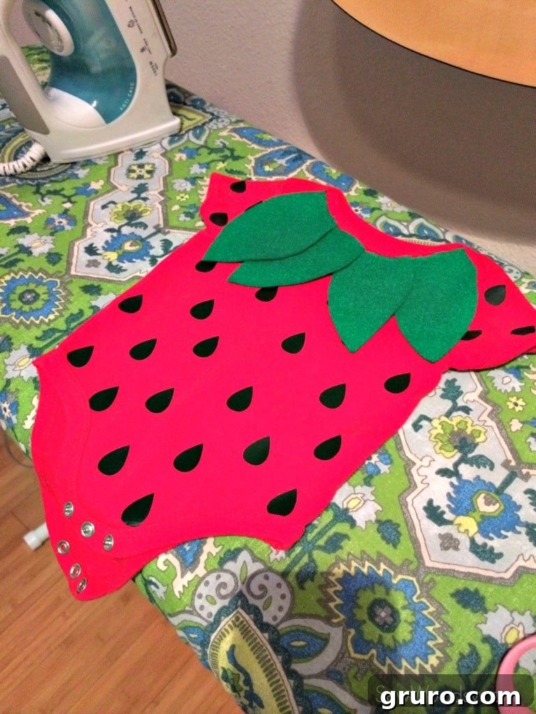 Sewing felt leaves onto the infant strawberry costume