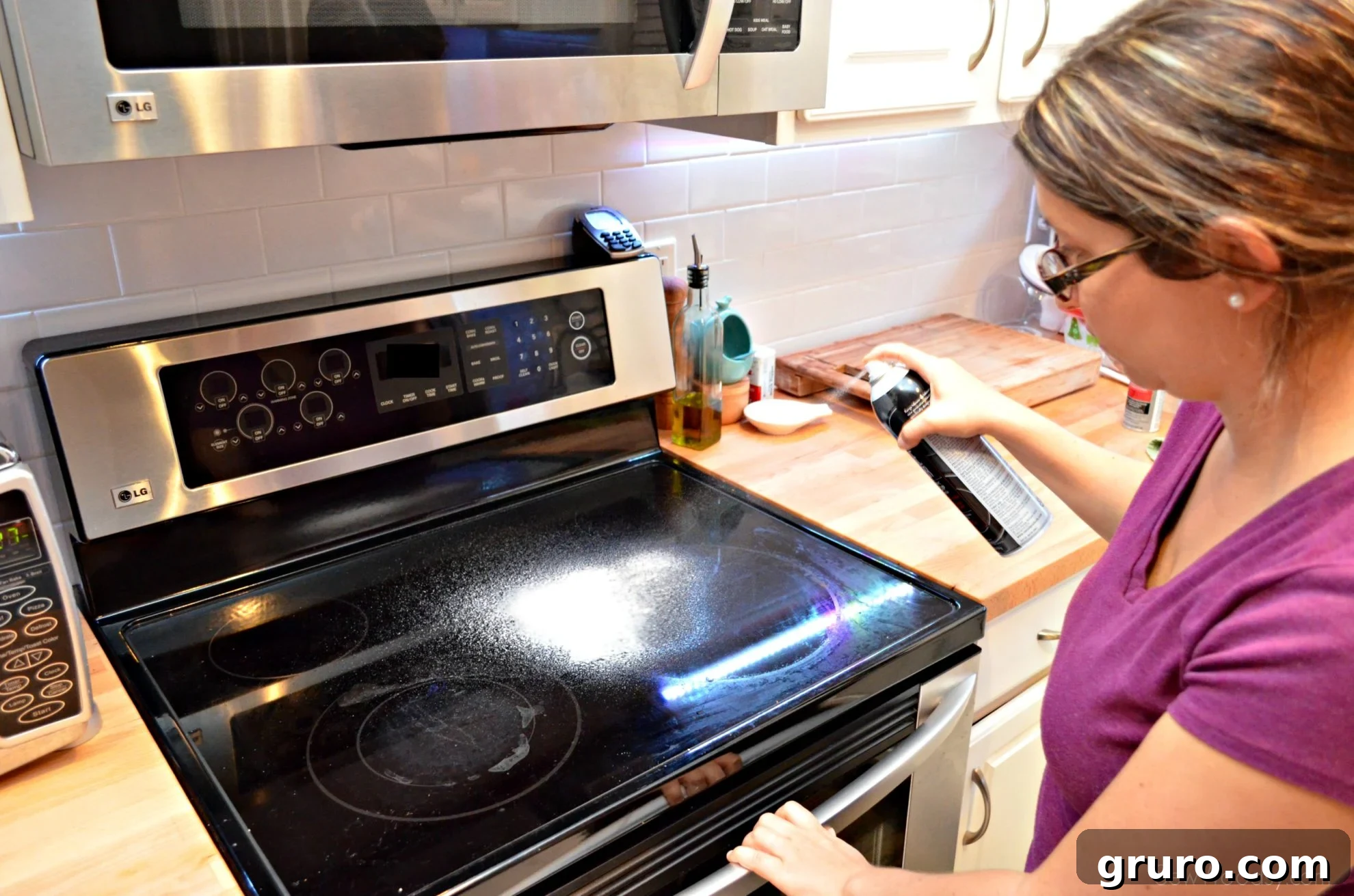 Applying Range Meister cleaner to a glass top stove to remove stubborn stains and restore its clarity.