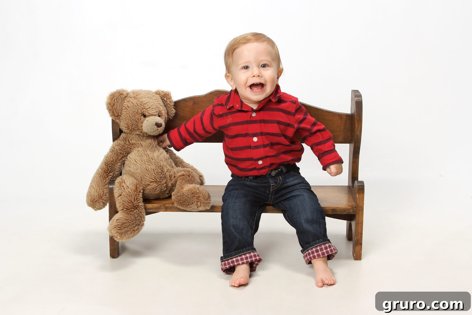 Romance in Focus 7 Little baby boy sitting on a wooden bench with a teddy bear next to him, looking sweet.