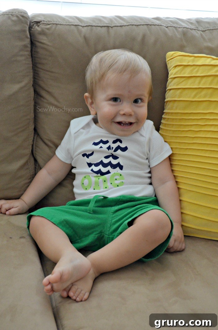 Adorable baby Ryder looking playfully off-camera while wearing his DIY first birthday onesie