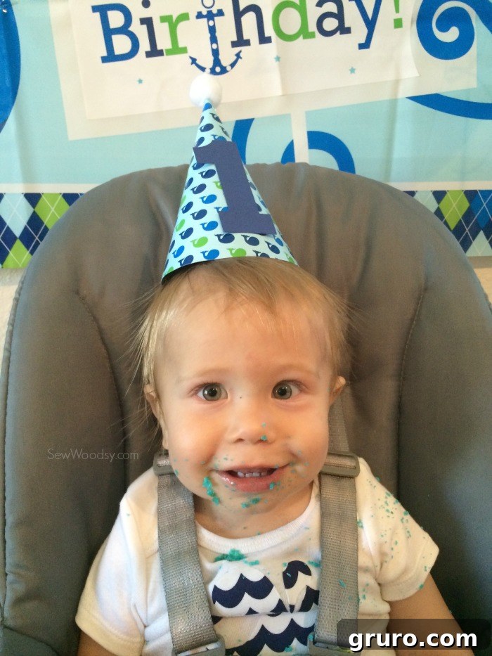 Baby Ryder proudly displaying a joyous cake smash aftermath in his DIY first birthday onesie