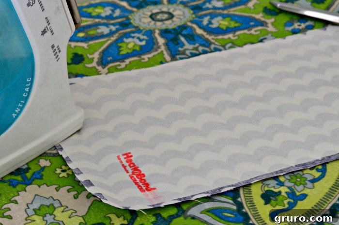 Ironing Heat 'n Bond adhesive onto the back of patterned fabric for a DIY onesie