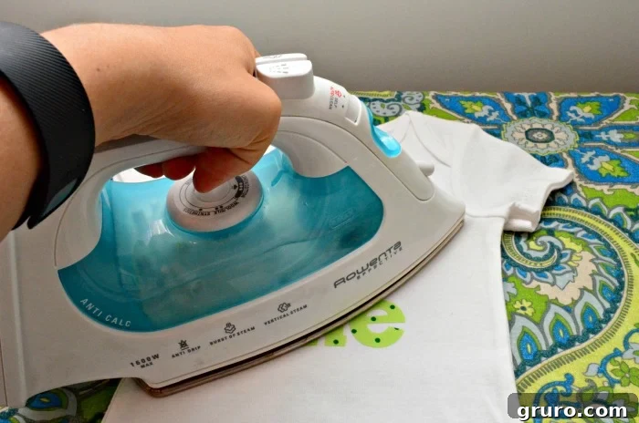 Ironing the fabric 'ONE' design onto the onesie with firm, even pressure for secure adhesion