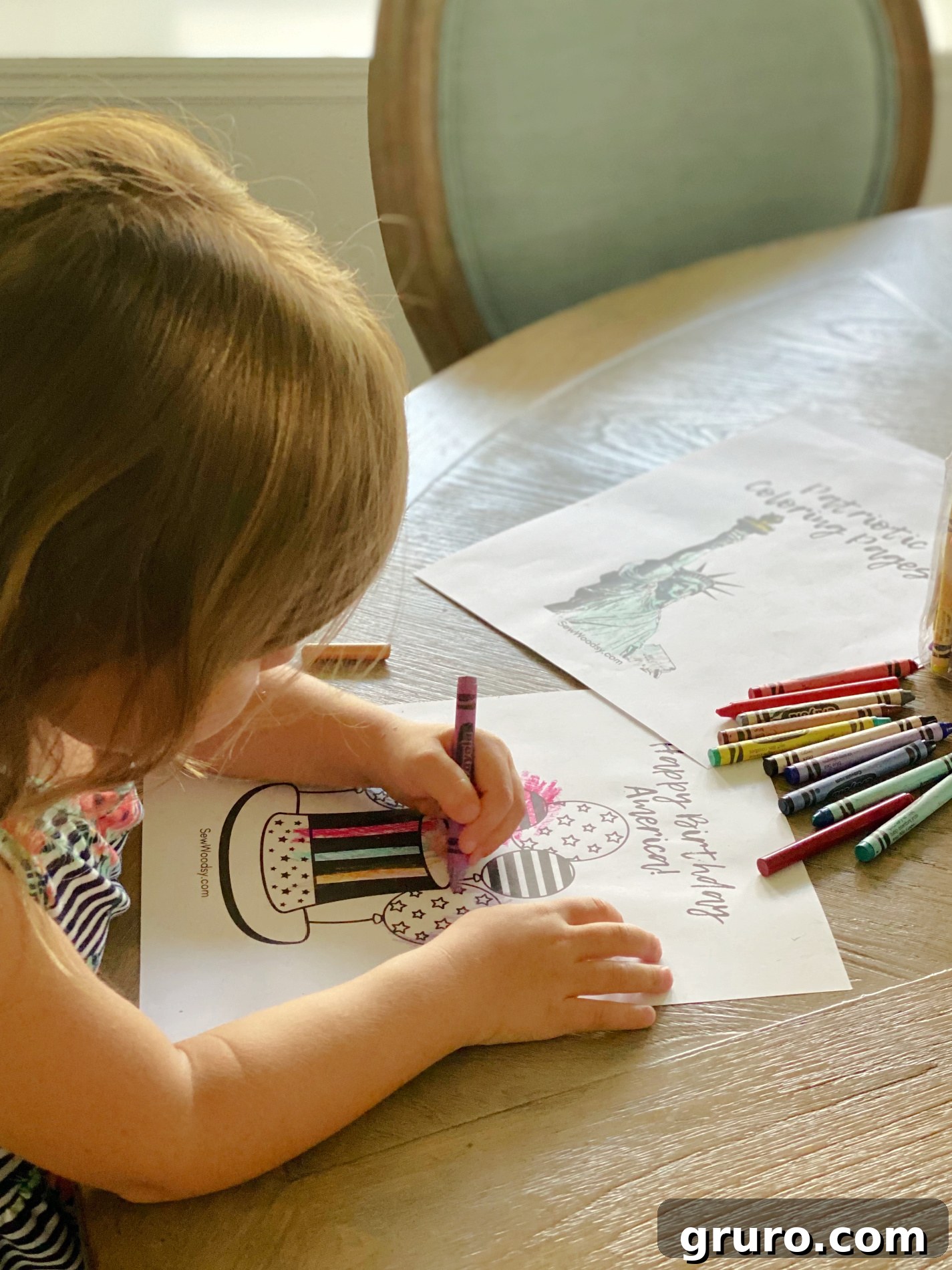 Little girl coloring at a wood table with crayons. 