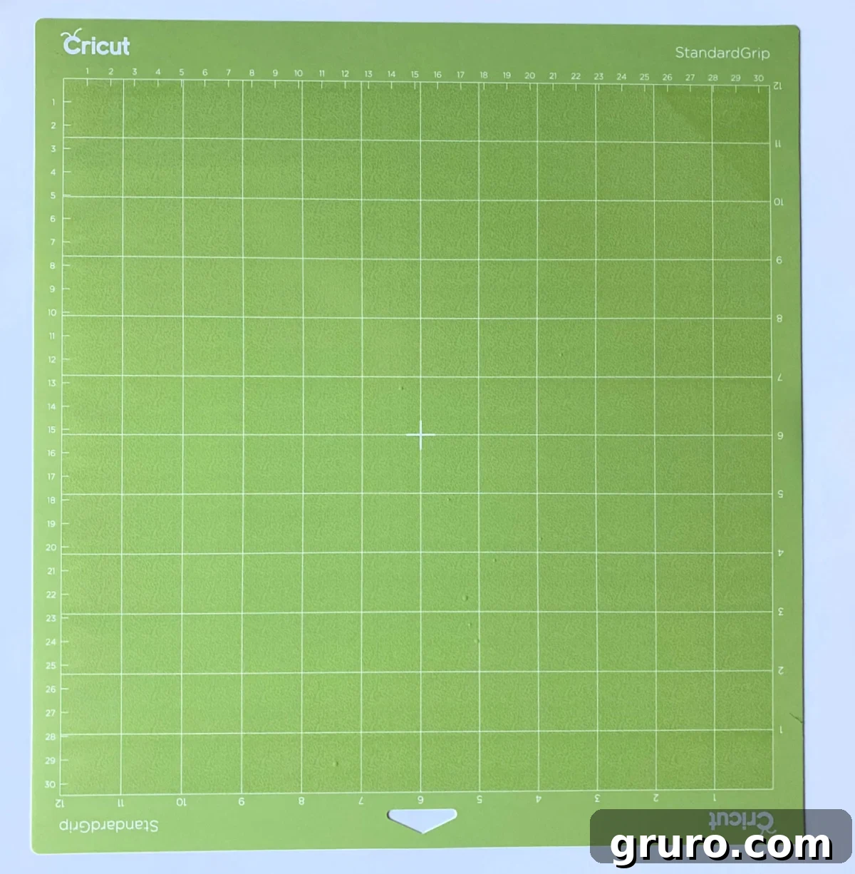 A vibrant neon green Cricut StandardGrip Mat resting on a pristine white surface, indicating its all-purpose adhesive strength for various crafting materials.