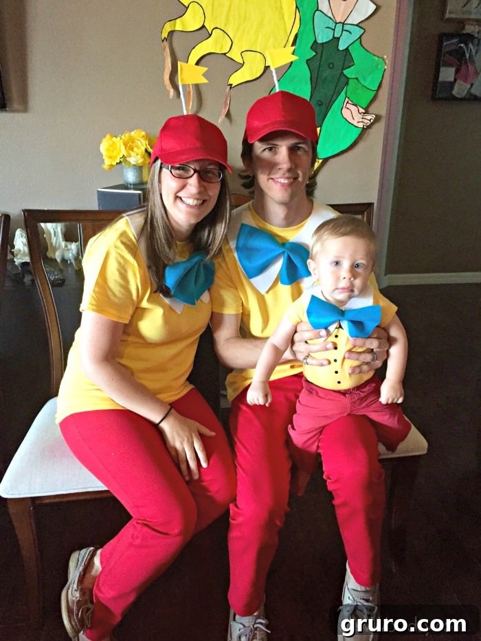 Effortless Tweedle Family Ensemble 7 Man, woman, and baby dressed as Tweedledum and Tweedledee sitting on chairs, posing playfully.