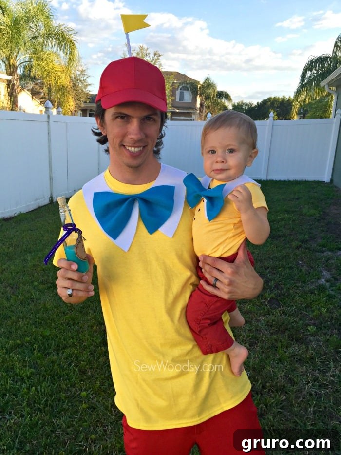 Effortless Tweedle Family Ensemble 9 Man holding a baby, both dressed as Tweedledum and Tweedledee, enjoying a themed drink at a party.