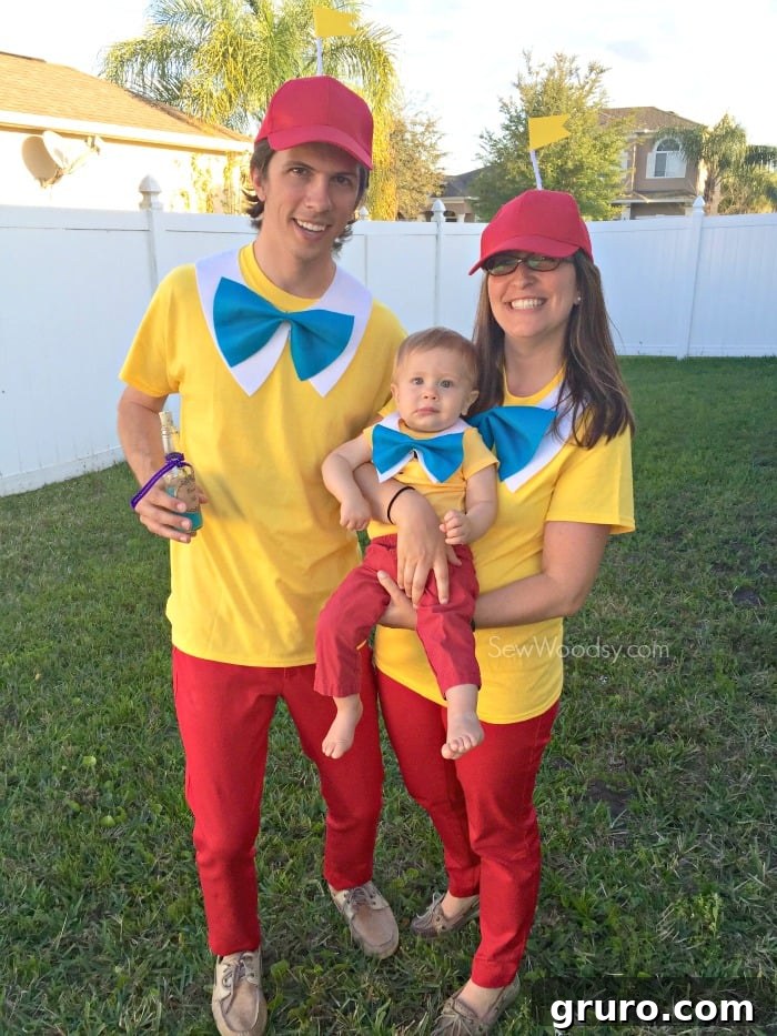 Effortless Tweedle Family Ensemble 10 Male, female, and baby dressed as Tweedledum and Tweedledee, standing in a vibrant green yard with a white picket fence.