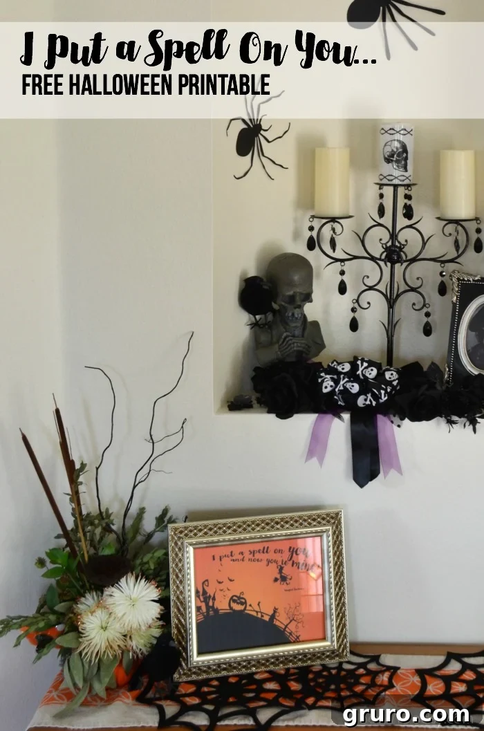 Halloween wall decor featuring a plant, spider webs, and a framed orange printable that reads "I put a spell on you".