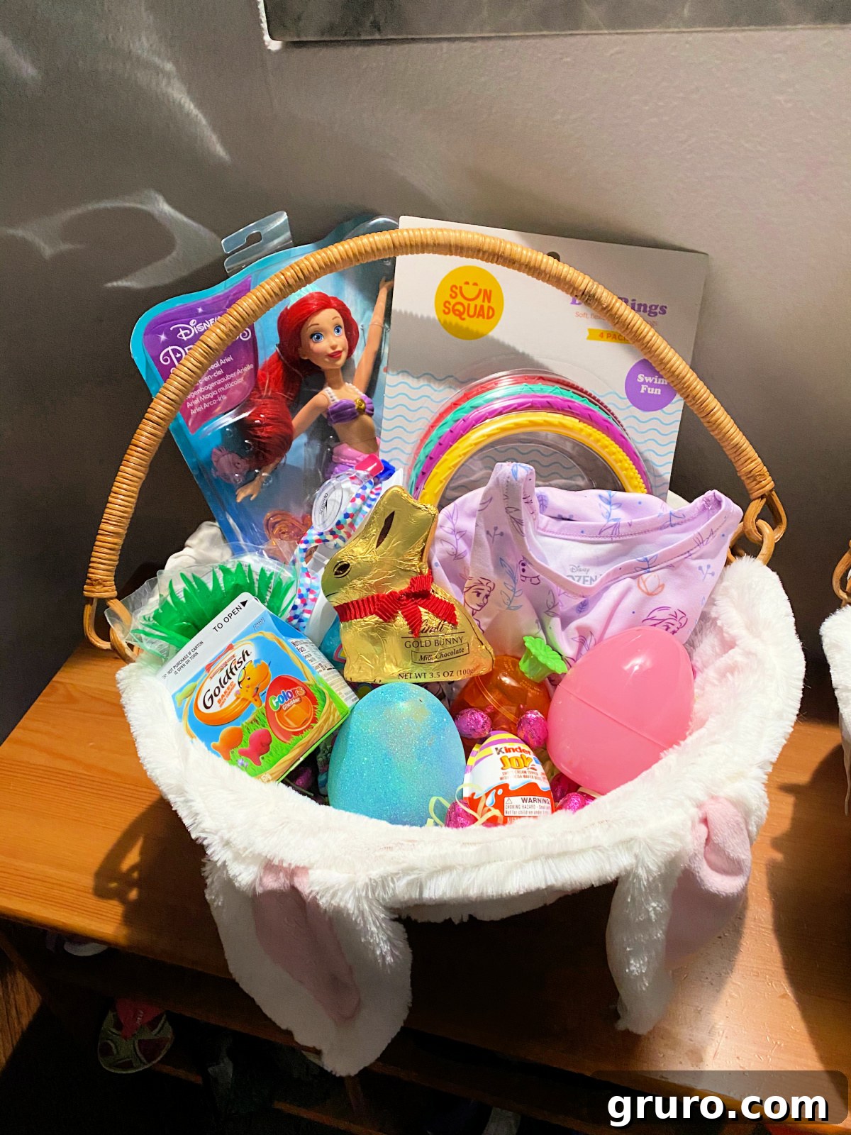 Magical Easter Basket Surprises for Youngsters 19 A girl's Easter basket filled with a mermaid Barbie, colorful plastic eggs, swim rings, and a few candies.