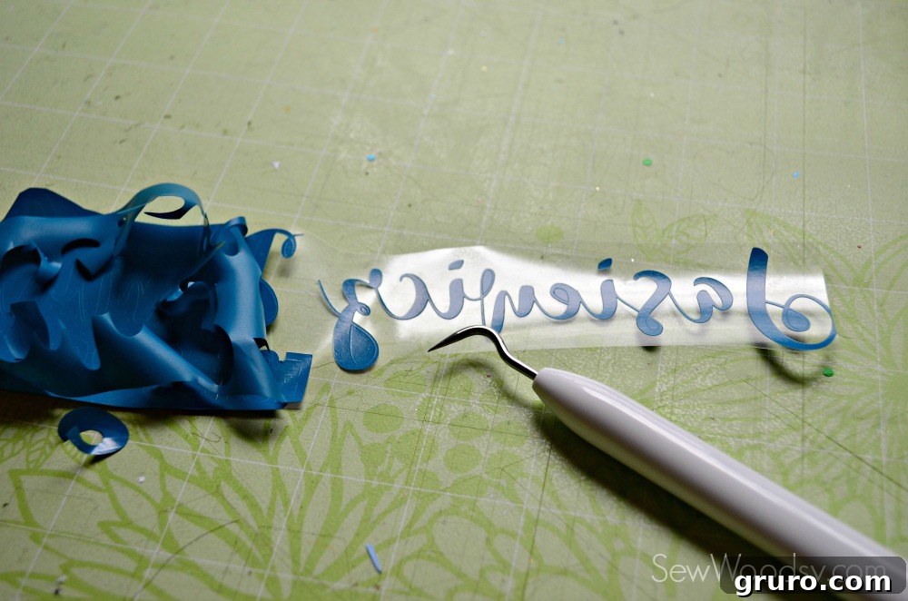 Close-up of using a weeding tool for intricate cursive font details on vinyl