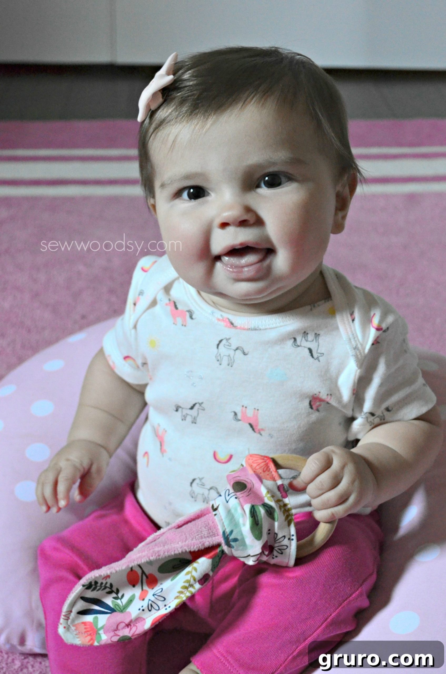 Baby girl holding a wooden teething ring with fabric.