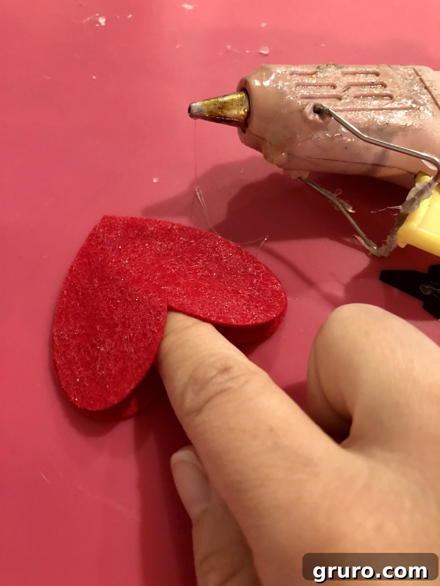 Gently opening the felt heart with a finger to create a pencil pocket