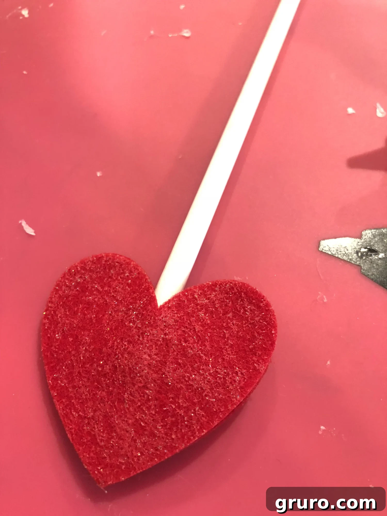 Inserting a pencil into the felt heart topper and pressing to secure