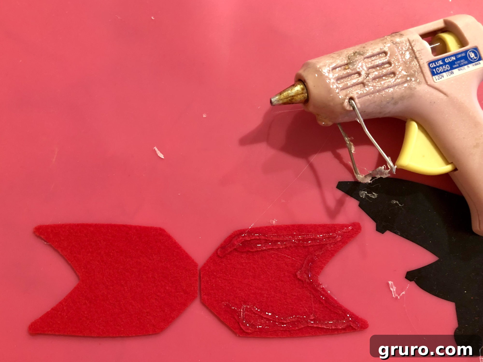 Hot gluing the felt arrow fletching onto the pencil's end