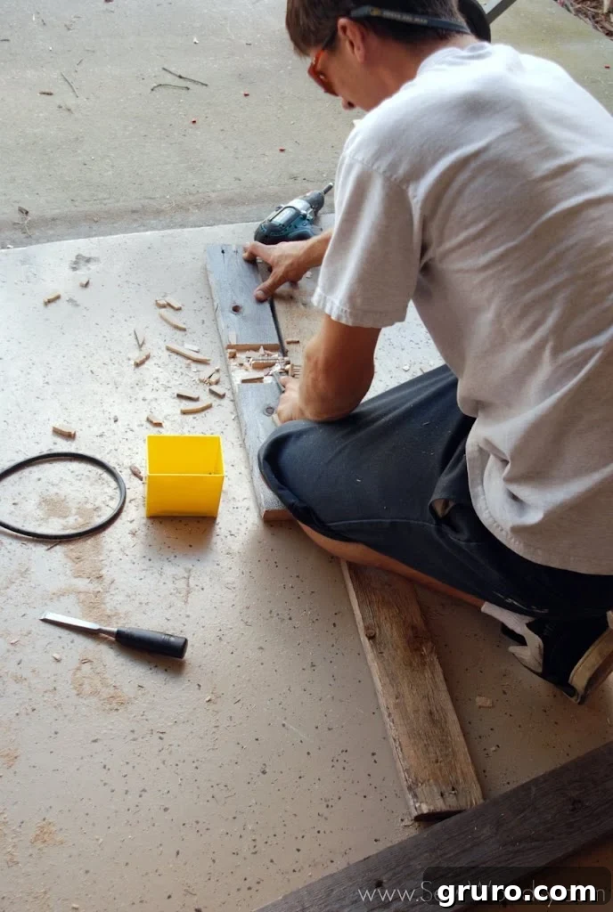 Eerie Tombstone Stakes 3 Man carefully chiseling a slot into a piece of recycled wood to create a lap joint for a Halloween grave cross.