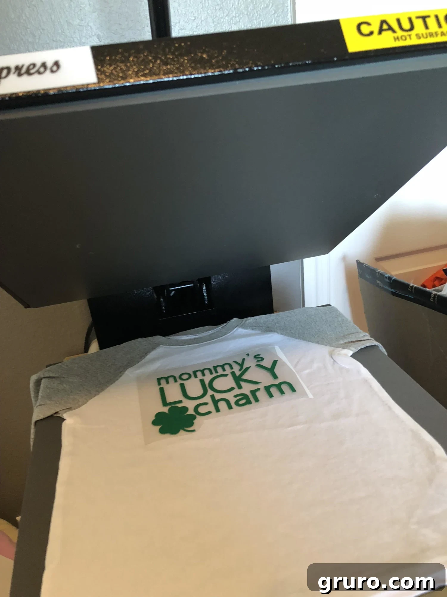 Talisman Tee 6 Applying 'Mommy's Lucky Charm' iron-on vinyl to a T-shirt with a heat press