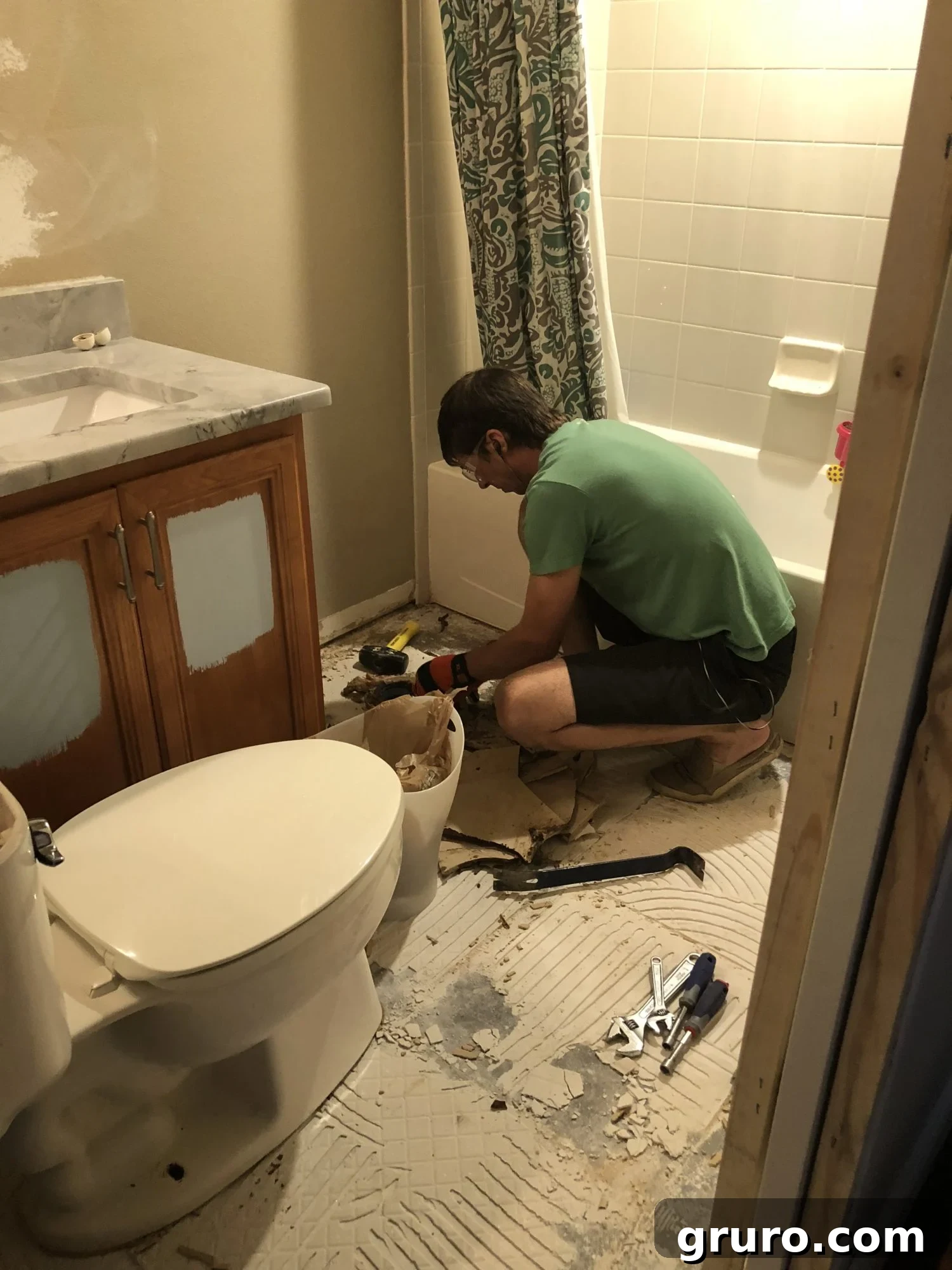 Removing bathroom floor tiles carefully into a bin