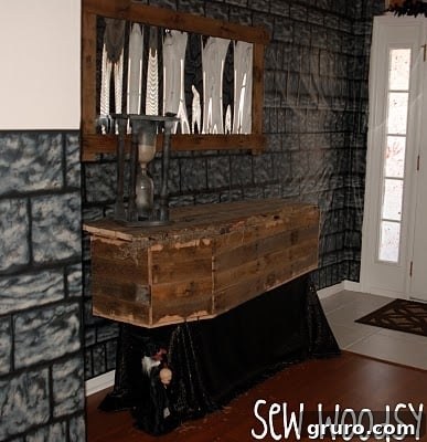 Side view of the decorated rustic Halloween coffin with moss, bugs, and creepy fingers.