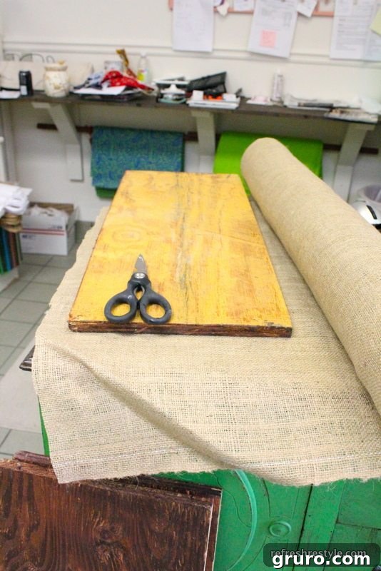 Cutting burlap fabric to cover repurposed wooden shelves