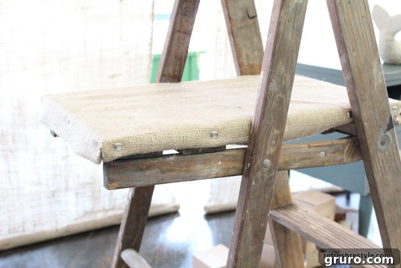 Securing burlap to wooden boards with thumb tacks for DIY shelves