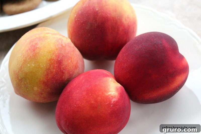 Close-up of three firm, ripe nectarines and three peaches, halved and pitted, showing their vibrant flesh.