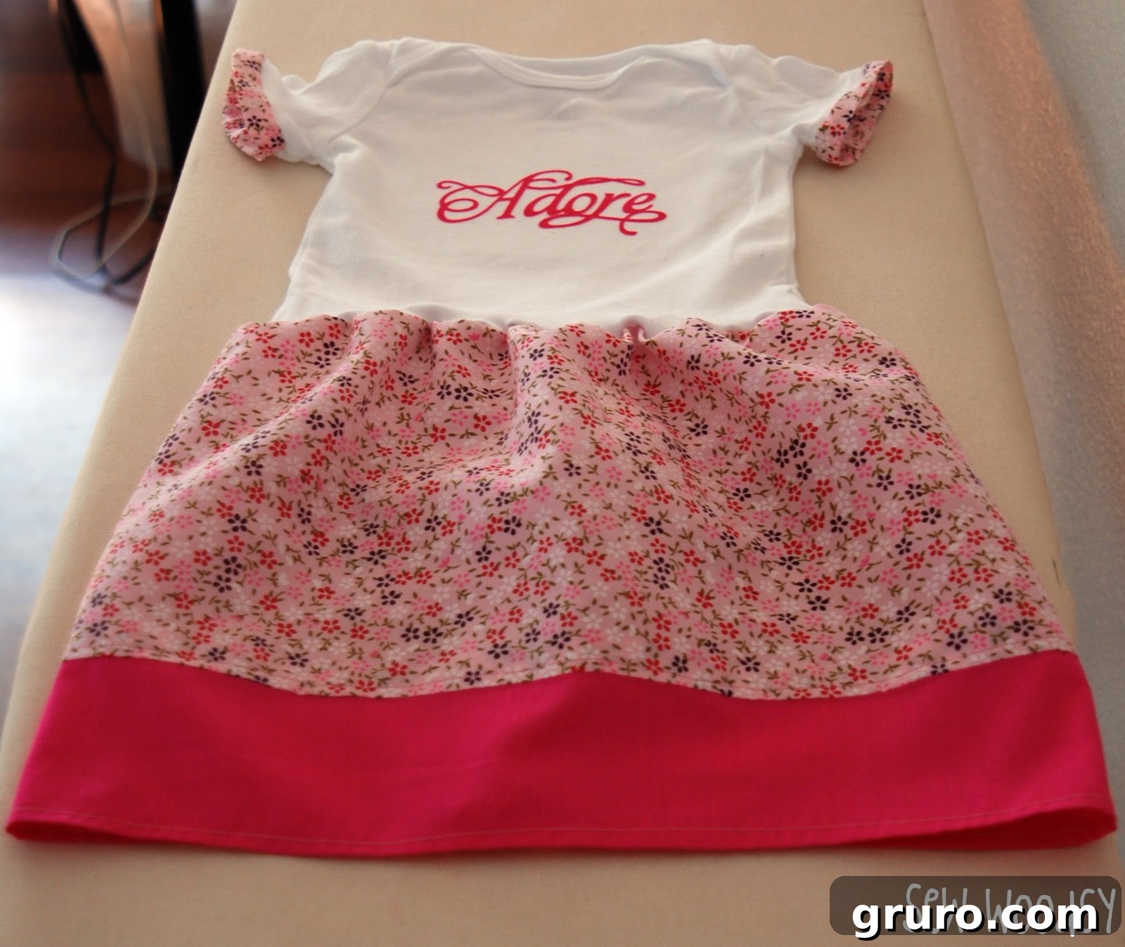 White top with flower skirt and pink trim on an ironing board, showcasing the assembled skirt detail.