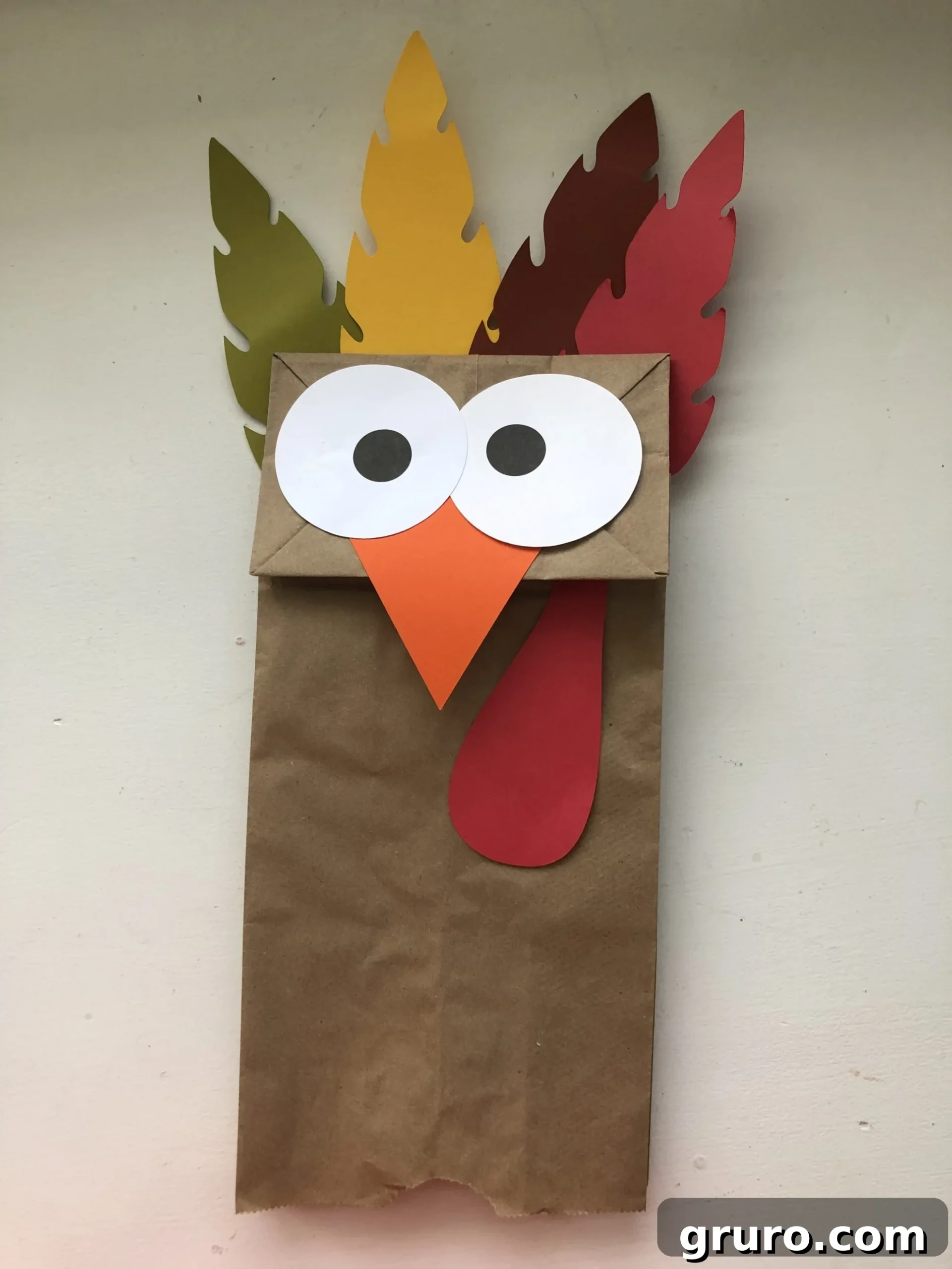 DIY Turkey Paper Bag Puppets 11 A single, delightful Turkey Paper Bag Puppet stands upright on a pristine white table, its unique character shining through and ready for imaginative play.