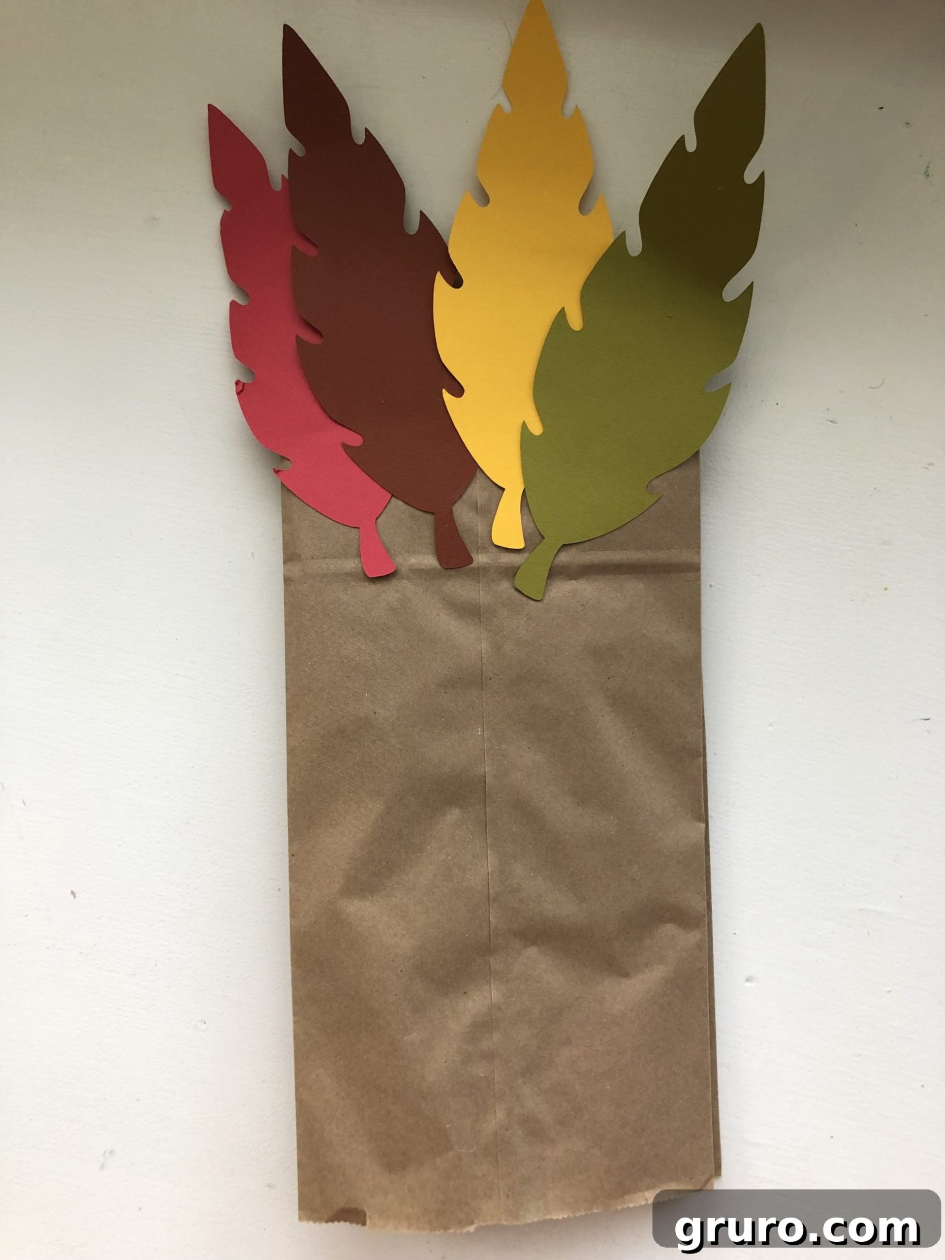 DIY Turkey Paper Bag Puppets 10 The back of a brown paper bag adorned with a vibrant, fanned arrangement of colorful paper feathers, showcasing the completed tail of a Turkey Paper Bag Puppet.