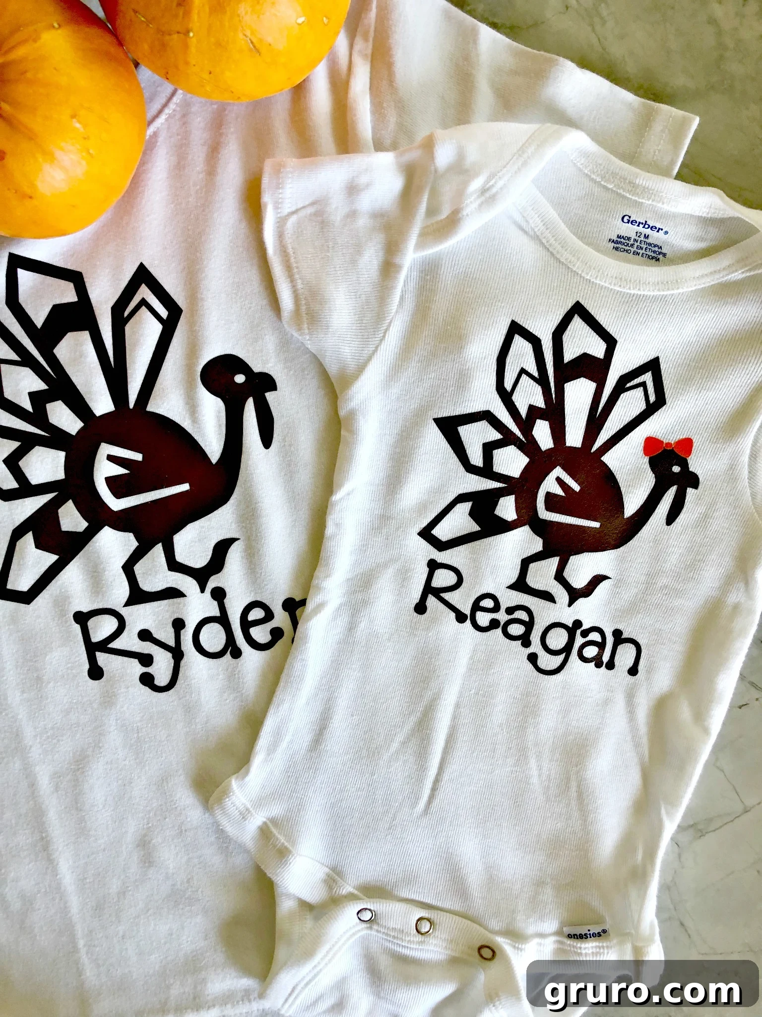 Two completed personalized Thanksgiving turkey shirts, featuring children's names, displayed alongside decorative pumpkins for a festive touch.