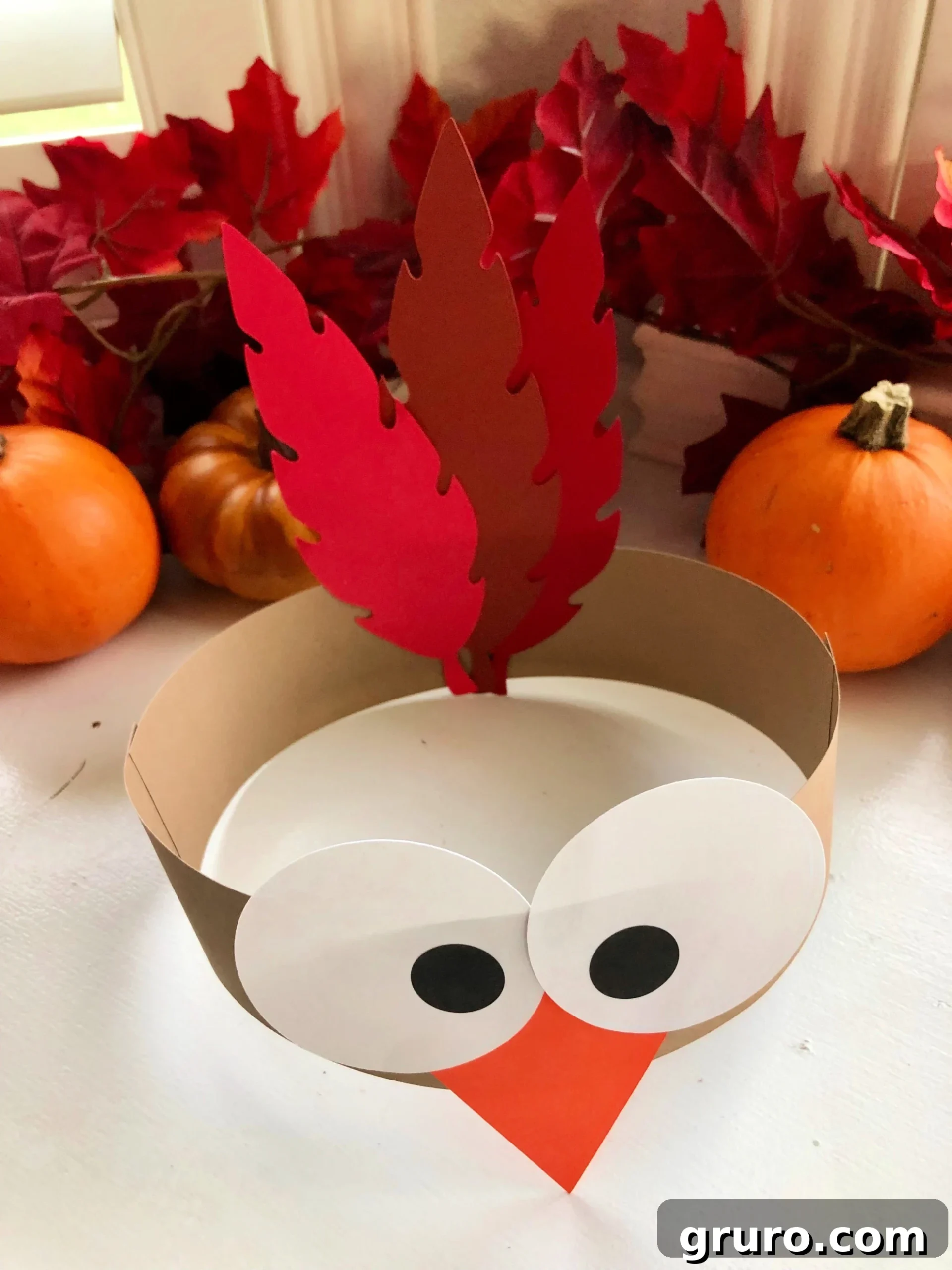 Top view of a turkey paper headband with fall leaves in the background.