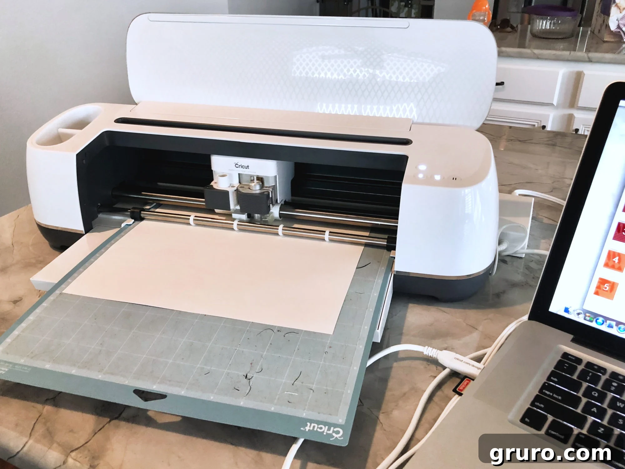 Cricut Maker loaded with white cardstock sitting on a marble countertop.