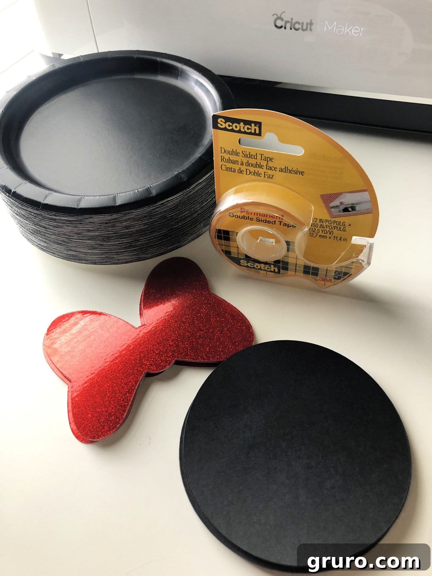 DIY Minnie Mouse Paper Plates Supplies - Materials needed for the craft project including Cricut machine, cardstock, and tape.