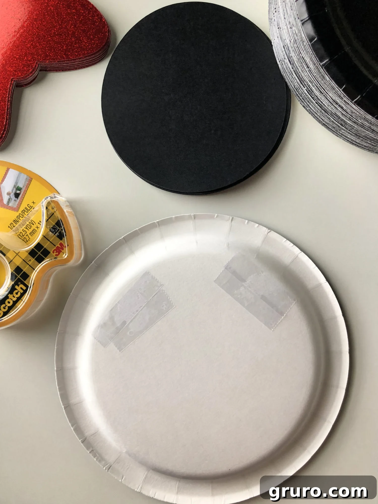 DIY Minnie Mouse Paper Plates Step 1 - Applying double-sided tape to the black paper plate.